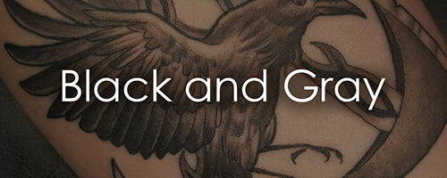 Close-up of a black-and-gray tattoo featuring a raven and an anchor, with the words 'Black and Gray' across it.